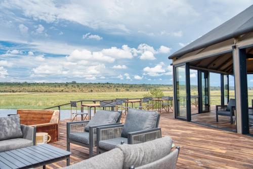 a wooden deck with chairs and tables on a roof at Chobe River Camp in Ngoma