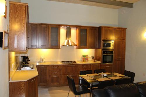 una cocina con armarios de madera y una mesa con sillas. en South Village Townhouse, en Żabbar