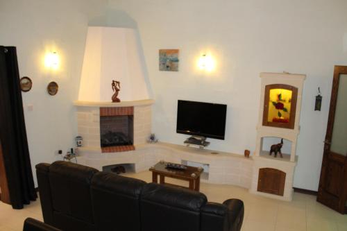 a living room with a tv and a fireplace at South Village Townhouse in Żabbar