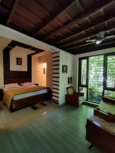 ein Schlafzimmer mit einem Bett und einem großen Fenster in der Unterkunft Periyaveettil Heritage in Neyyāttinkara