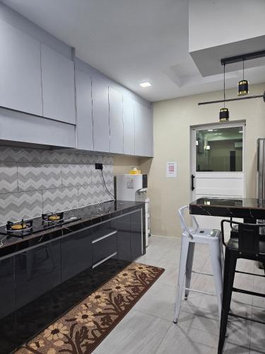 a kitchen with white cabinets and a black counter top at Macchiato Homestay in Klang
