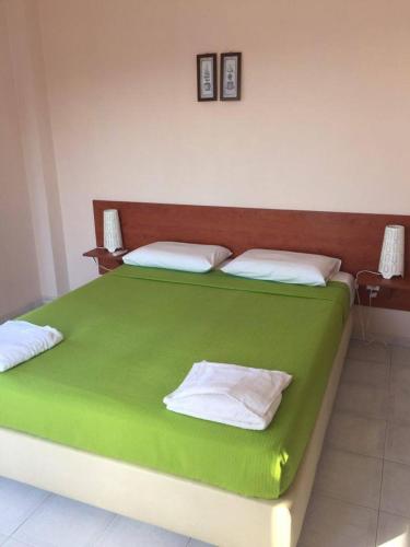 zielone łóżko z białymi poduszkami w pokoju w obiekcie Aprilis Apartments w mieście Kiónion