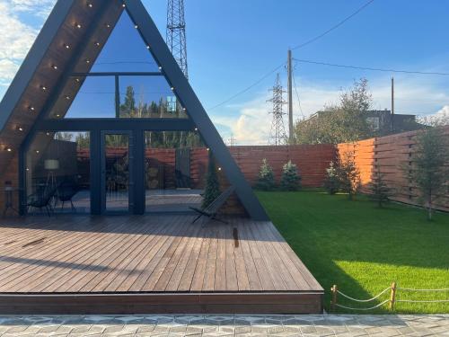 a pavilion with a wooden deck in a garden at A-Frame LUX in Pavlodar