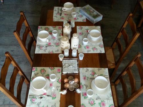 a wooden table with plates and cups and dishes on it at La Maison Des Badons in Saint-Basile