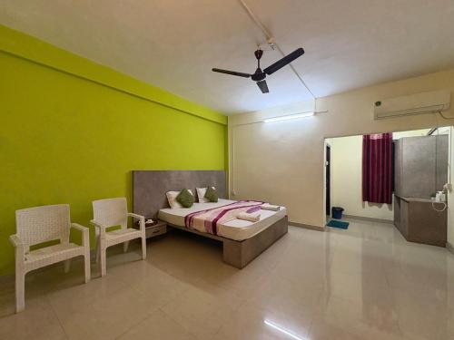 a bedroom with green walls and a bed and two chairs at The rolling hills Kaziranga in Hatikhuli