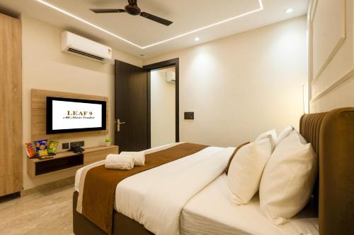 a hotel room with a bed and a flat screen tv at Leaf 9 Grand, Near Udyog vihar and Yashobhoomi in Gurgaon