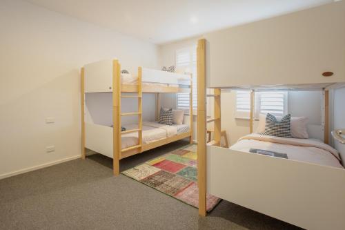 a room with two bunk beds and a bedroom at Bridge Beach House Central Barwon Heads Sleeps 12 Walk everywhere Accessible lower level bedroom and bathroom in Barwon Heads