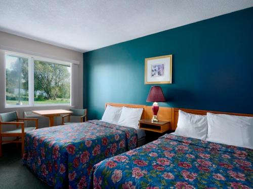 Habitación de hotel con 2 camas y pared azul en Save Inn en Kincardine