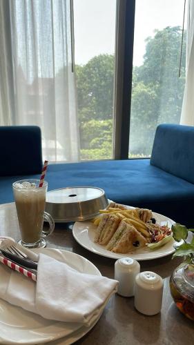 a table with a plate of food and a drink at Aarchh Regency Noida in Noida