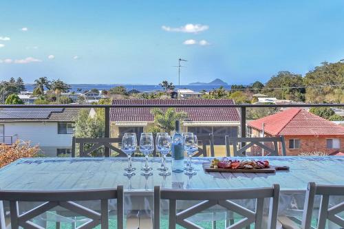 a table with wine glasses on top of a balcony at Oasis at Salamander Bay in Salamander Bay