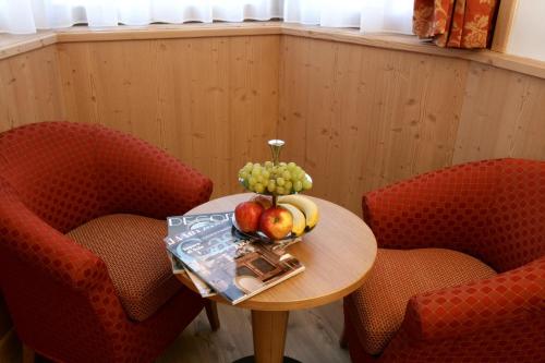 a table with a bowl of fruit on it with two chairs at Hotel Garni La Roccia in Andalo