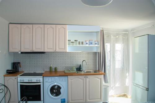 a kitchen with white cabinets and a washing machine at Skyline Loft in Mytilini