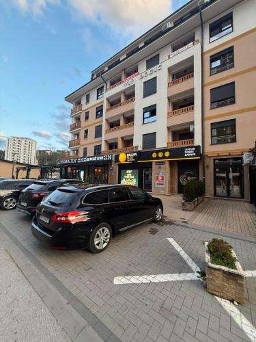 a parking lot with cars parked in front of a building at Apartman Vip Aleksa Zlatibor Centar in Zlatibor