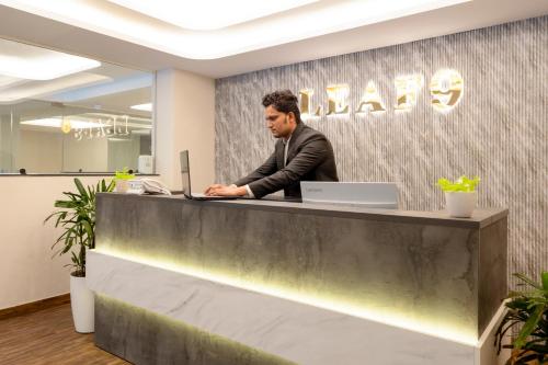 a man sitting at a counter in an office at Leaf 9 Grand, Near Udyog vihar and Yashobhoomi in Gurgaon