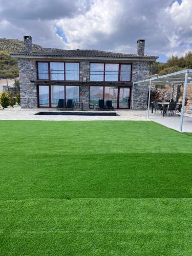 a stone house with a lawn in front of it at Modern Stone Villas with Swimming Pool in Aliveri