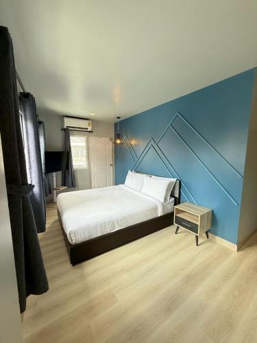 a bedroom with a large bed and a blue wall at The August Hostel in Chiang Mai