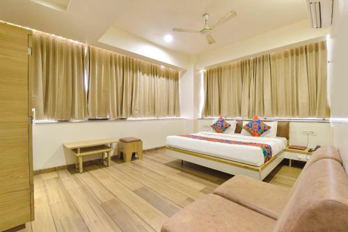 a bedroom with a bed and a couch and a window at FabHotel Soham Palace in Jāmb