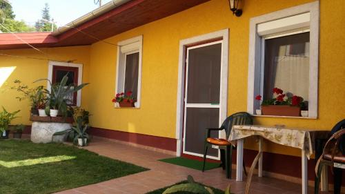 a yellow house with a table and windows at Zách Klára utcai Apartman in Visegrád