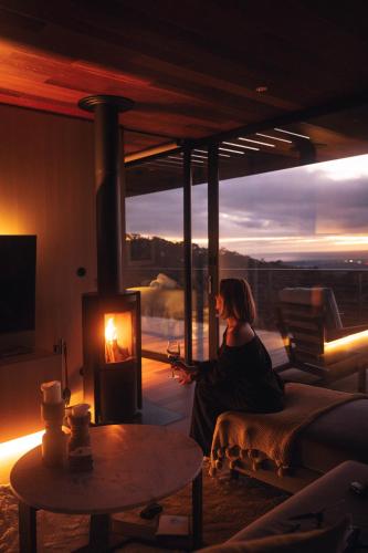 una mujer sentada en una sala de estar con chimenea en Willunga Ridge, en Willunga