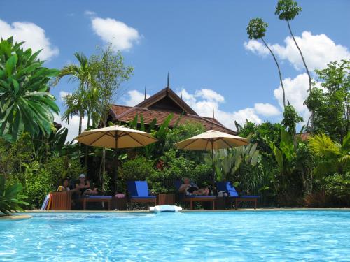 a pool at a resort with people sitting under umbrellas at Oriental Siam Resort - SHA Extra Plus Certified in Chiang Mai