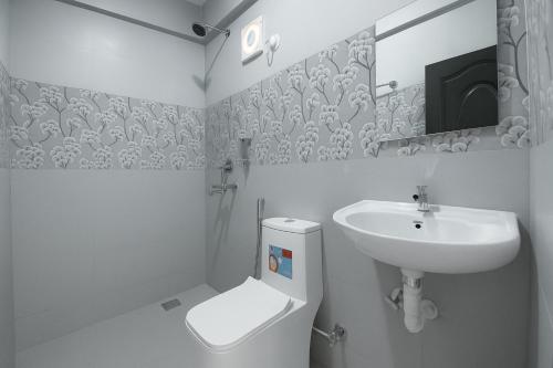 a white bathroom with a sink and a toilet at Quadruple Comfort Calangute Goa in Calangute