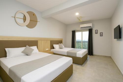 a hotel room with two beds and a window at Quadruple Comfort Calangute Goa in Calangute