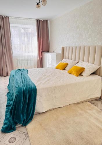 a bedroom with a large white bed with yellow pillows at Биржан Сал центр 2 к in Taldykorgan