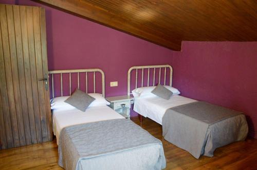 two beds in a room with purple walls at Mas Sabaters - L'Era de Sabaters in Tavernoles