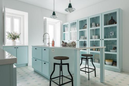 een keuken met blauwe kasten en 2 barkrukken bij Casa C'Alma in Lissabon