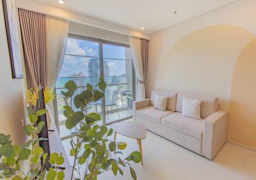 a living room with a couch and a large window at The Song Your House Apartment - Căn Hộ Du Lịch Biển Vũng Tàu in Vung Tau