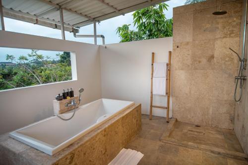 a bathroom with a tub and a window at Kayun Retreat Mas Suite in Ubud