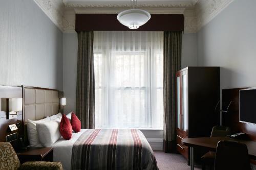 um quarto de hotel com uma cama e uma janela em The Grand at Trafalgar Square em Londres