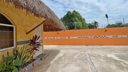 a yellow building with a thatched roof and a driveway at Maya Dreams Bacalar in Bacalar