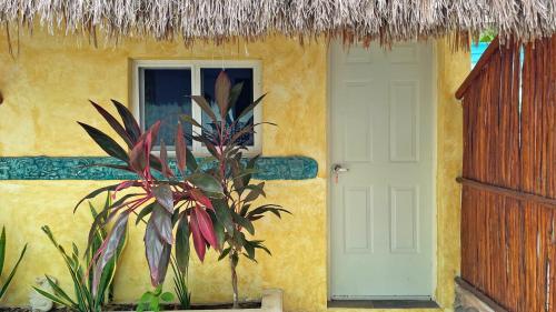 a yellow house with a white door and a window at Maya Dreams Bacalar in Bacalar