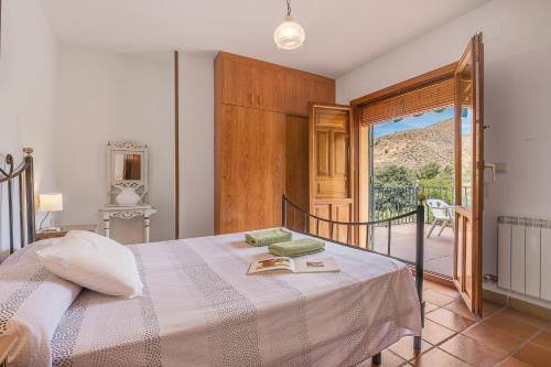 a bedroom with a bed and a view of a balcony at Casa Hitos in Monachil