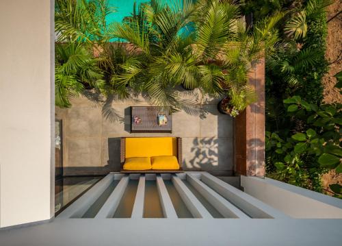 a yellow bench in a room with plants at La Viola, 3BHK Villa with rooftop Jacuzzi, close to Anjuna & Vagator Beach with Private Pool, Kitchen, Terrace in Anjuna