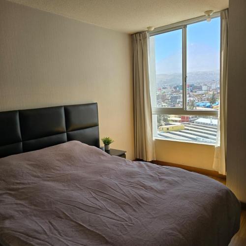 a bedroom with a bed and a large window at Departamento Arequipa- PERUMIN 2025 in Paucarpata
