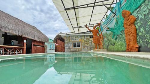 a swimming pool with statues in front of a building at Maya Dreams Bacalar in Bacalar