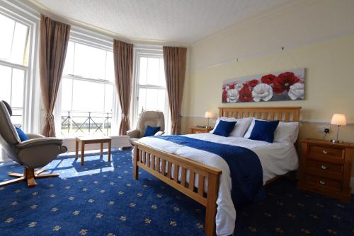 a bedroom with a bed and a chair and windows at No.18 in Lowestoft