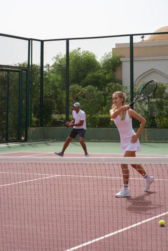two people playing tennis on a tennis court at The Club by Fanar in Salalah