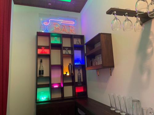 a bar with a neon sign and some wine glasses at Enara Holiday Home in Nikawatawana
