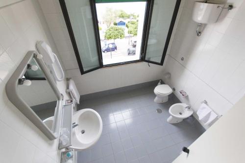 a bathroom with a toilet and a sink and a window at Albergo Palazzo in Santa Cesarea Terme