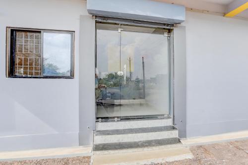 a glass door on a white building with stairs at Hotel O RIO in Durg