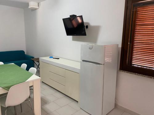 a kitchen with a refrigerator and a tv on a wall at Appartamento Smeraldo Pochi passi dal mare in Calasetta