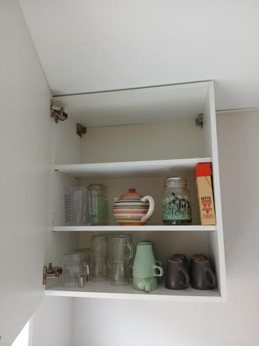 a white cupboard filled with lots of kitchen items at Ruim en rustig chalet in Nationaal park de Drentsche Aa max 5 prs in Anloo