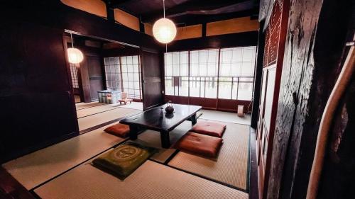a living room with a table and chairs and windows at 古民家宿 孫八 - Mago8 in Maibara