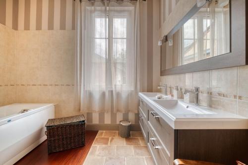 a bathroom with a tub and a sink and a bath tubermottermott at La Demeure De Jeanne in Cadours