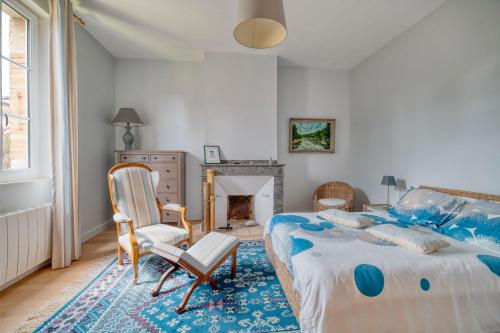 a bedroom with a bed and a chair and a fireplace at La Demeure De Jeanne in Cadours