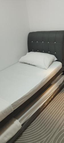 a bed with a white pillow on top of it at Luxe Cozy Haven in Cybersouth in Kampung Dengkil