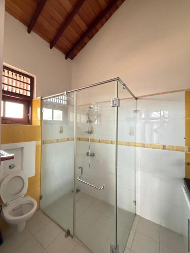 a bathroom with a glass shower and a toilet at Hotel Transylvania - Negombo in Negombo